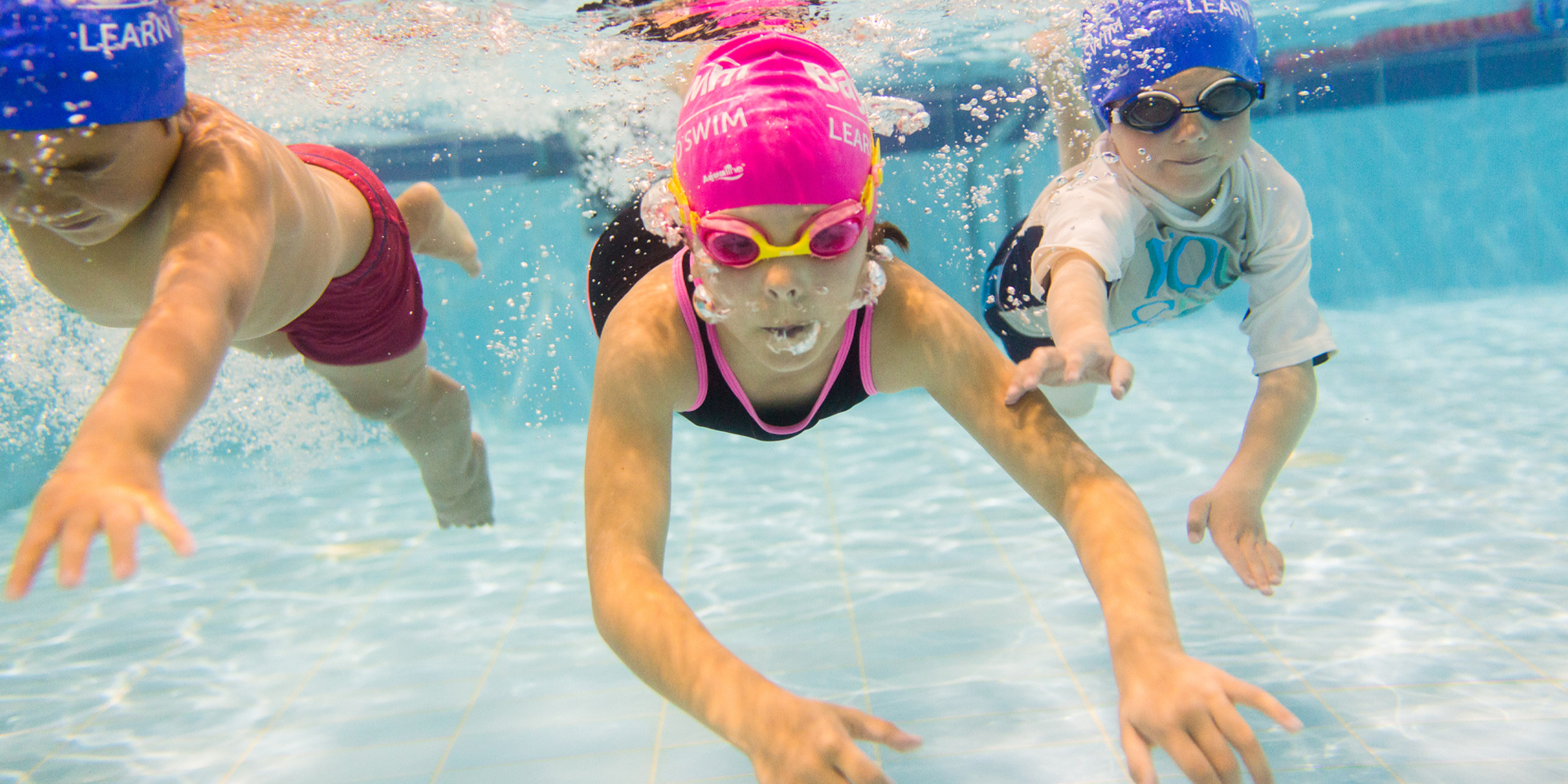 Three children swimming together underwater